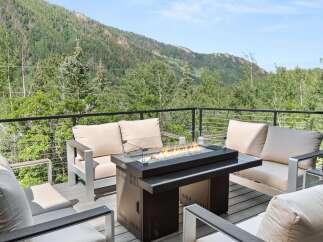Experience breathtaking mountain views from this stunning deck, complete with a modern fire pit and comfortable seating.