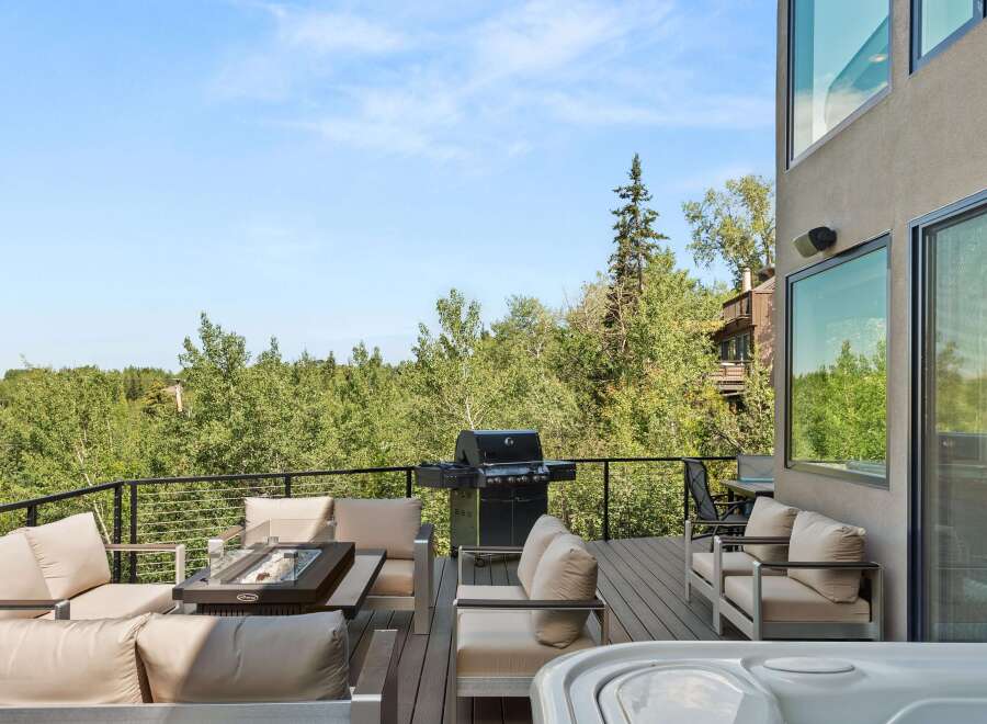 Experience luxury outdoor living with this stunning deck featuring a spacious hot tub and a sleek gas grill, perfect for entertaining.