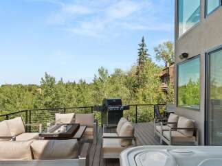 Experience luxury outdoor living with this stunning deck featuring a spacious hot tub and a sleek gas grill, perfect for entertaining.