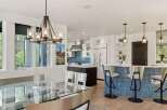 Experience modern luxury in this open-concept living space, featuring a sleek glass dining table and a stunning blue tiled kitchen island with bar seating.