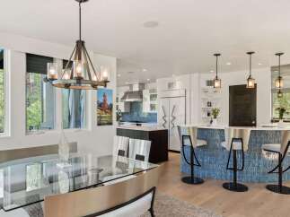Experience modern luxury in this open-concept living space, featuring a sleek glass dining table and a stunning blue tiled kitchen island with bar seating.