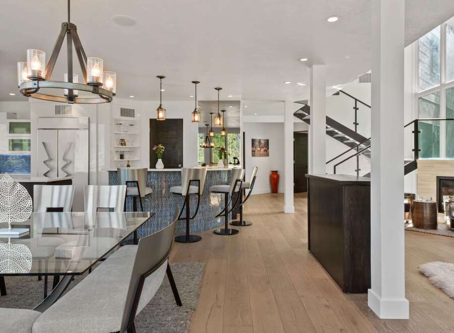 Experience modern luxury in this open-concept living space, featuring a sleek kitchen island with bar seating and a striking mosaic backsplash.