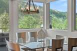 Experience breathtaking mountain views from this elegant dining room, featuring a sleek glass-top table and modern chairs.
