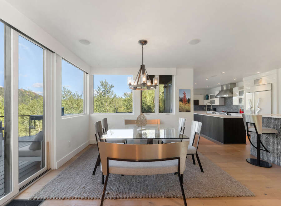 Experience modern living in this stunning home featuring a spacious dining area with a sleek glass-top table and comfortable seating, perfect for entertaining.