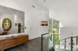 This modern entryway features a large, ornate mirror reflecting the natural light pouring in from the expansive windows.