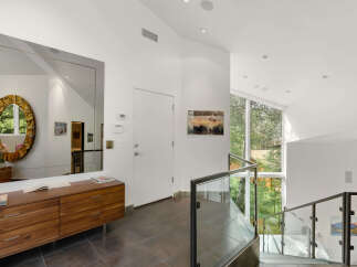This modern entryway features a large, ornate mirror reflecting the natural light pouring in from the expansive windows.