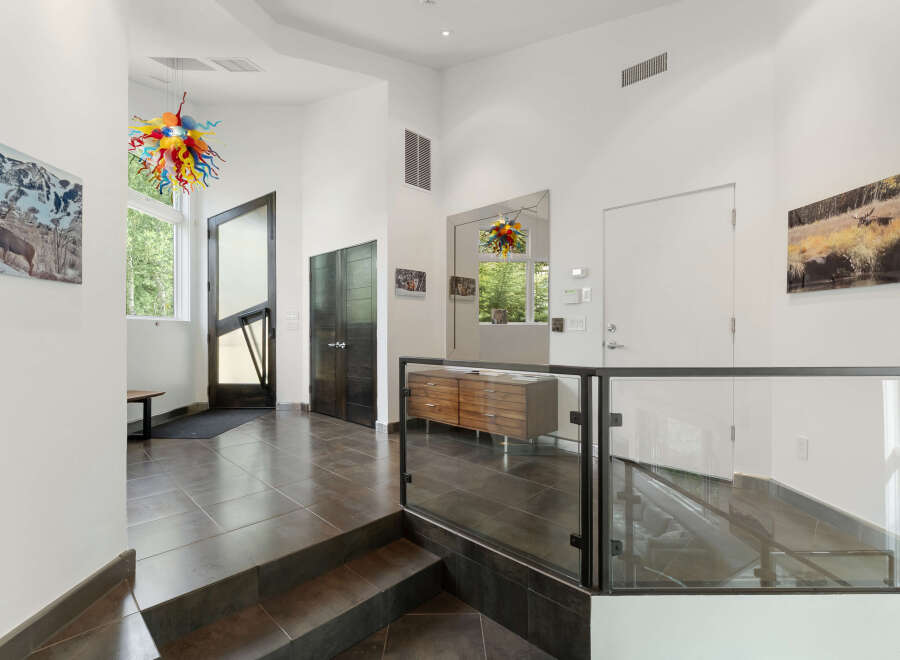 Step into this modern entryway featuring a striking multi-colored glass chandelier that adds a vibrant pop of color.