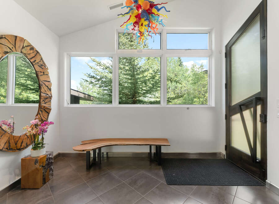 Step into this welcoming entryway featuring a striking live-edge wood bench and a unique, artistic chandelier.