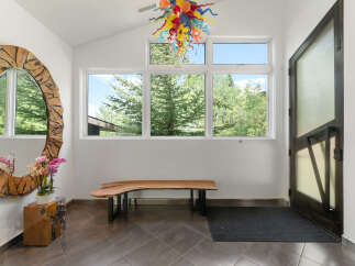 Step into this welcoming entryway featuring a striking live-edge wood bench and a unique, artistic chandelier.