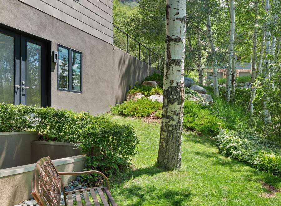Enjoy the serene outdoor living space with a charming metal bench perfect for relaxing amidst lush greenery.