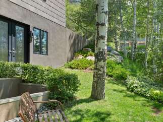 Enjoy the serene outdoor living space with a charming metal bench perfect for relaxing amidst lush greenery.