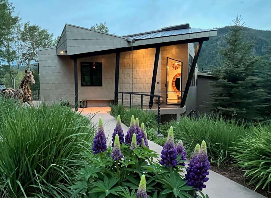 Discover modern mountain living in this stunning architectural home, featuring a unique metal exterior and a welcoming entryway with vibrant art.