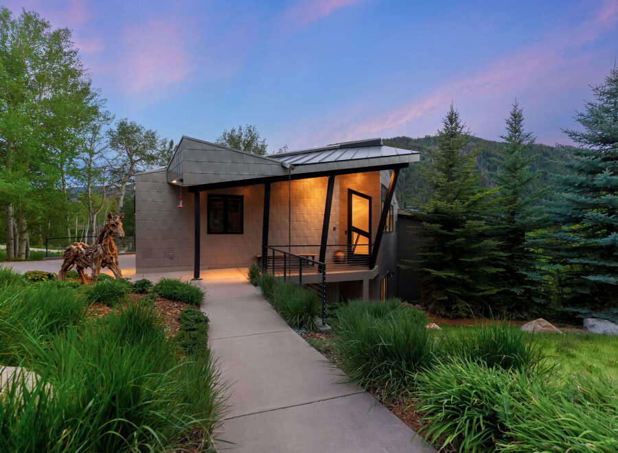 Experience modern mountain living in this stunning architectural home, featuring a unique metal exterior and a dramatic angled roofline.