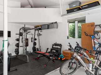 This spacious garage offers a dedicated home gym area with a Marcy weight machine, adjustable bench, and a full set of dumbbells, perfect for your fitness routine.