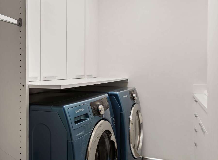 Discover modern convenience in this laundry room, featuring a stacked Samsung washer and dryer set in a sleek blue finish.