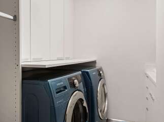 Discover modern convenience in this laundry room, featuring a stacked Samsung washer and dryer set in a sleek blue finish.