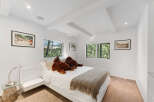 This bright and airy bedroom features a modern white platform bed adorned with two large teddy bears and a cozy knit throw.