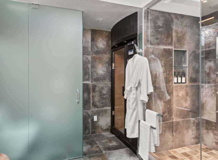 Experience ultimate relaxation in this luxurious bathroom featuring a private sauna and a spacious glass-enclosed shower.