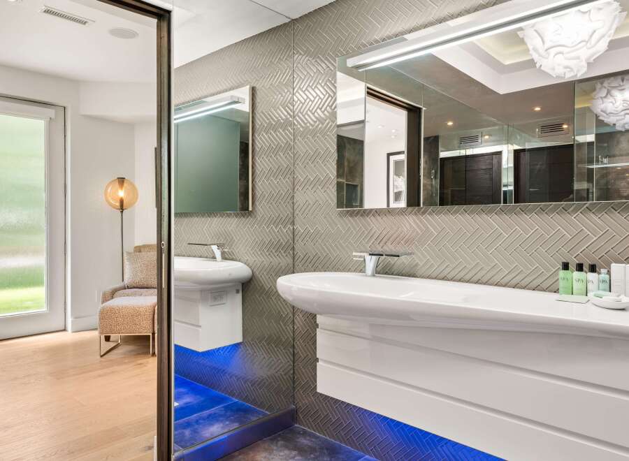 Experience modern luxury in this stunning bathroom, featuring a sleek floating vanity and a striking herringbone tile backsplash.