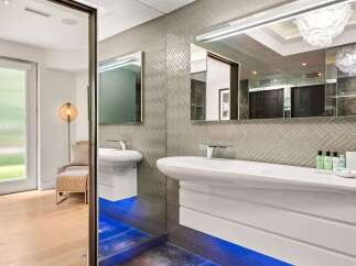 Experience modern luxury in this stunning bathroom, featuring a sleek floating vanity and a striking herringbone tile backsplash.
