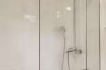 Experience modern elegance in this bathroom featuring a sleek glass shower enclosure over a pristine white bathtub.