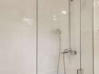 Experience modern elegance in this bathroom featuring a sleek glass shower enclosure over a pristine white bathtub.