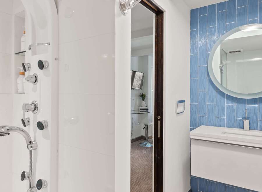 Experience modern luxury in this bathroom featuring a sleek white shower system with multiple jets and a handheld showerhead.