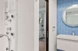 Experience modern luxury in this bathroom featuring a sleek white shower system with multiple jets and a handheld showerhead.