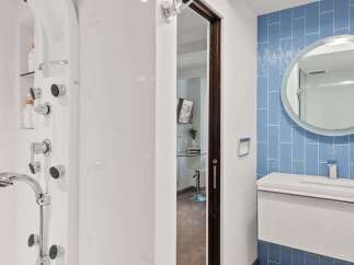 Experience modern luxury in this bathroom featuring a sleek white shower system with multiple jets and a handheld showerhead.