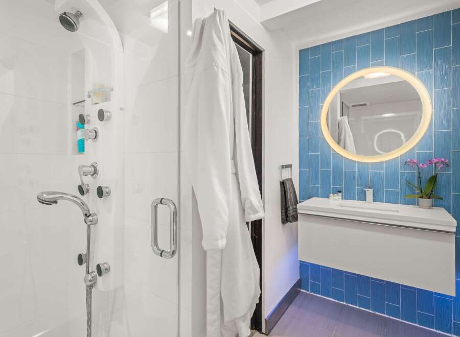 Experience luxury in this modern bathroom featuring a spacious walk-in shower with multiple showerheads and a sleek vanity with a vessel sink.