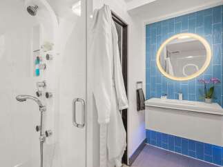 Experience luxury in this modern bathroom featuring a spacious walk-in shower with multiple showerheads and a sleek vanity with a vessel sink.