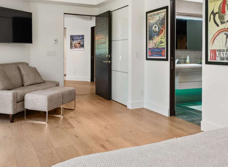 Experience modern luxury in this spacious bedroom featuring a comfortable seating area with a patterned sofa and ottoman, perfect for relaxation.
