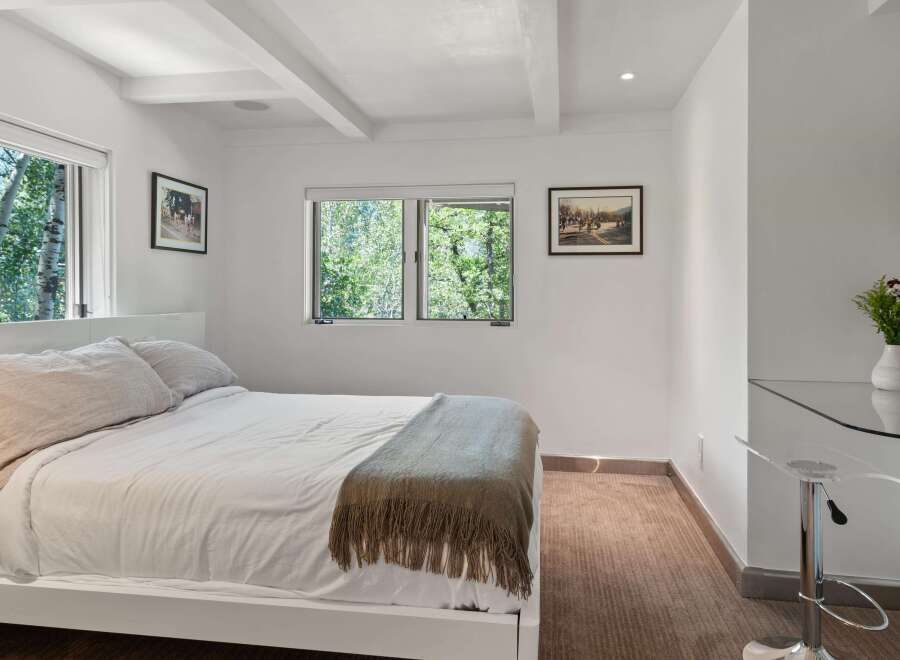 Experience serene living in this charming bedroom, featuring a comfortable bed adorned with plush linens and a cozy throw blanket.