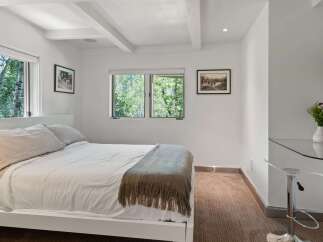 Experience serene living in this charming bedroom, featuring a comfortable bed adorned with plush linens and a cozy throw blanket.