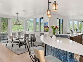 Experience luxury living in this stunning open-concept kitchen and dining area, featuring a sleek white quartz island with a striking blue mosaic tile backsplash.