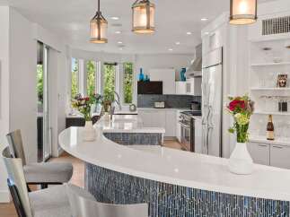 Experience modern luxury in this stunning kitchen, featuring a sleek white countertop island with a captivating blue mosaic tile base.