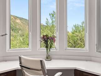 Enjoy breathtaking mountain views from this elegant home office featuring a spacious built-in desk and a comfortable white leather executive chair.