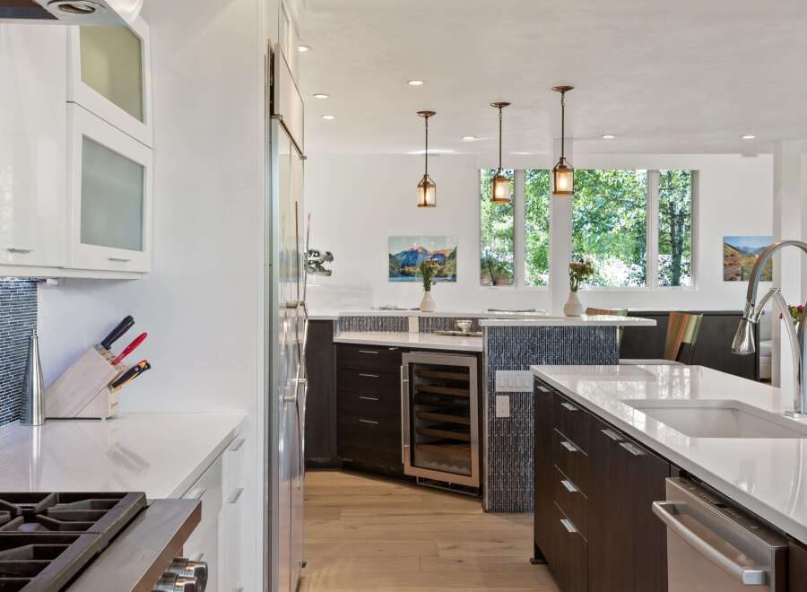 Experience luxury in this modern kitchen featuring sleek dark wood cabinetry and a spacious white quartz island.