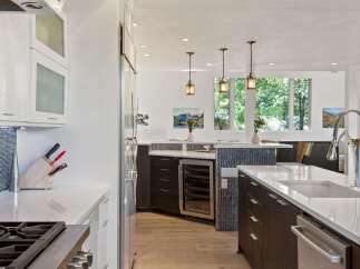 Experience luxury in this modern kitchen featuring sleek dark wood cabinetry and a spacious white quartz island.