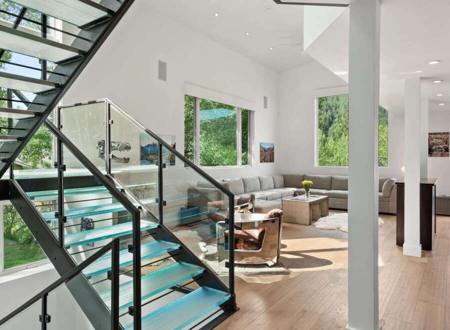 Experience modern luxury with this stunning home featuring a striking glass and metal staircase with integrated LED lighting.
