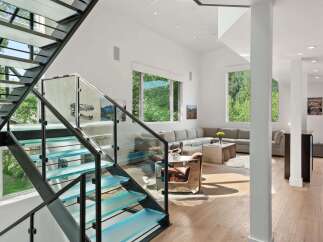 Experience modern luxury with this stunning home featuring a striking glass and metal staircase with integrated LED lighting.