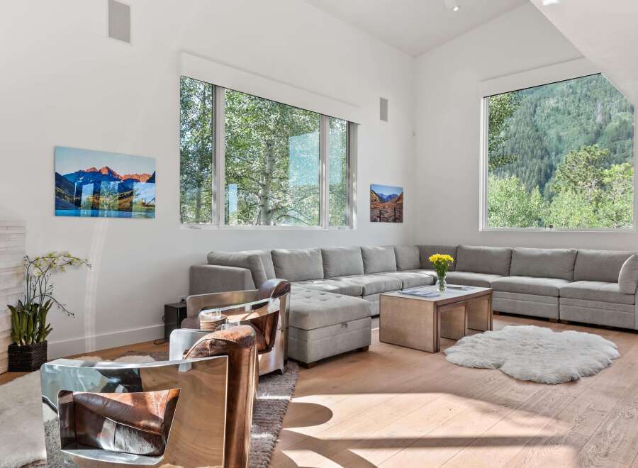 Experience luxury living in this spacious living room, featuring a large sectional sofa perfect for gatherings and a stunning view of the surrounding mountains through expansive windows.