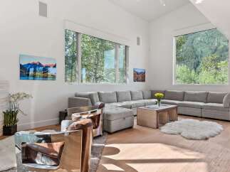 Experience luxury living in this spacious living room, featuring a large sectional sofa perfect for gatherings and a stunning view of the surrounding mountains through expansive windows.