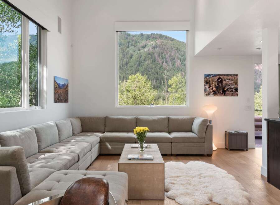 Experience breathtaking mountain views from this stunning living room, featuring a spacious sectional sofa perfect for relaxation.