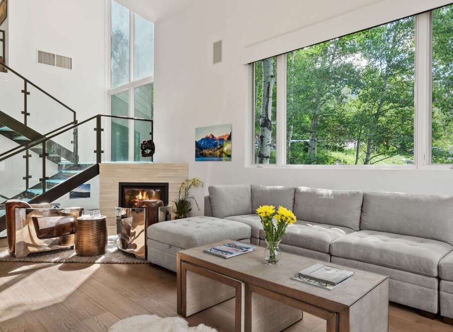 Experience luxury living in this stunning modern home featuring a grand fireplace and a soaring ceiling with expansive windows.