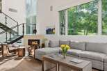 Experience luxury living in this stunning modern home featuring a grand fireplace and a soaring ceiling with expansive windows.