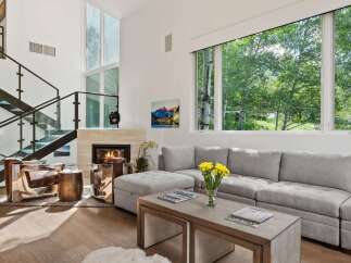 Experience luxury living in this stunning modern home featuring a grand fireplace and a soaring ceiling with expansive windows.