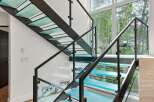 Experience modern luxury with this stunning staircase featuring illuminated glass treads and sleek metal railings.