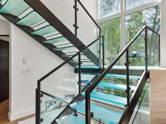 Experience modern luxury with this stunning staircase featuring illuminated glass treads and sleek metal railings.