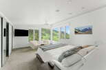 Experience luxury mountain living in this stunning bedroom featuring panoramic views of lush green hills and snow-capped peaks through expansive windows.